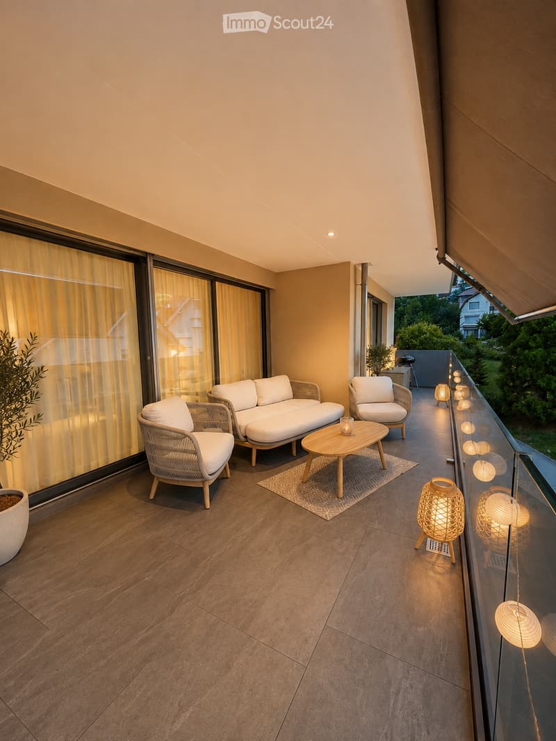 Modern balcony with wooden flooring, white wicker furniture, a coffee table, and decorative lamps.