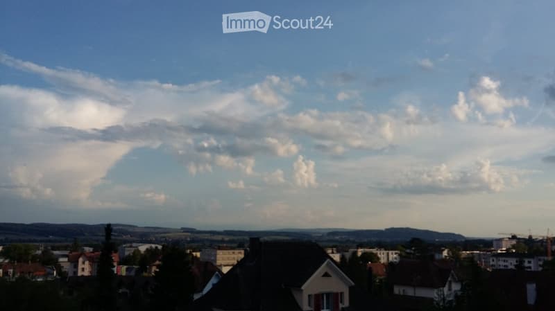 Townscape view, distant mountains, clear blue sky with clouds
