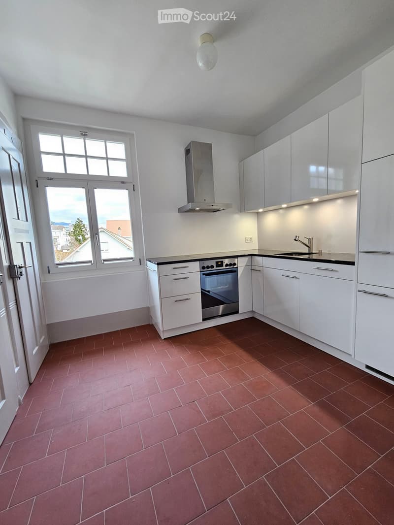 Modern kitchen with tiled floor, white cabinets, modern appliances, sink, exhaust hood, window