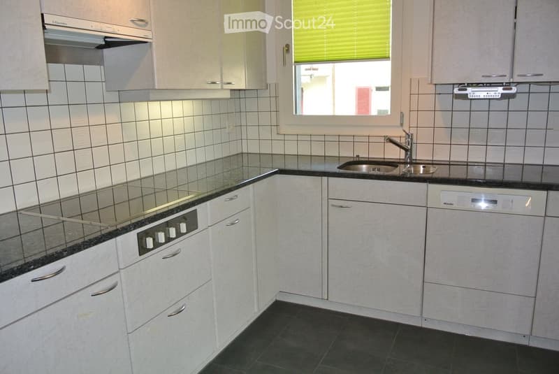 Modern kitchen with white cabinets, black countertops, stainless steel sink, and built-in appliances.