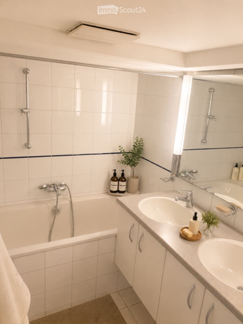Modern bathroom with white tiled walls, a bathtub, double sink vanity with mirrored cabinet, and decorative plants.