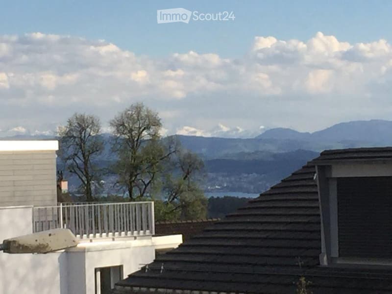 Balcony with white railing overlooking a scenic mountain and lake view.