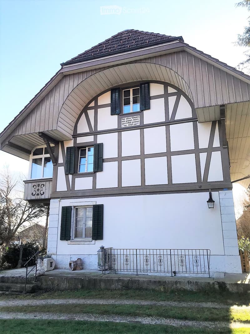 Traditional house, white and brown exterior, multiple windows, balcony, black railings, lamp
