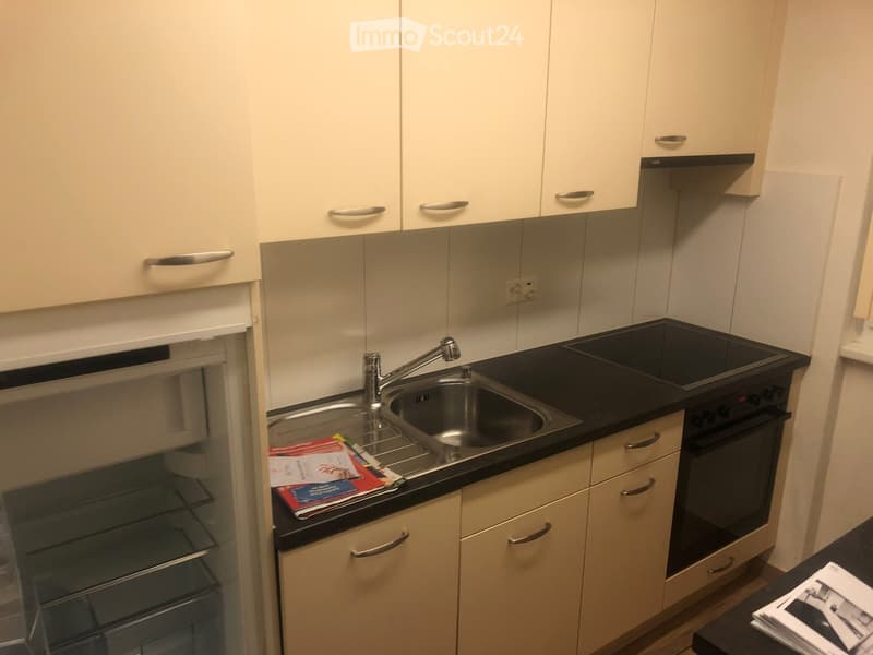 Modern kitchen with white cabinets, black countertop, stainless steel sink, and built-in oven.