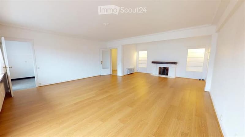Empty room with light wooden flooring, white walls, and a fireplace. No furniture or equipment present.