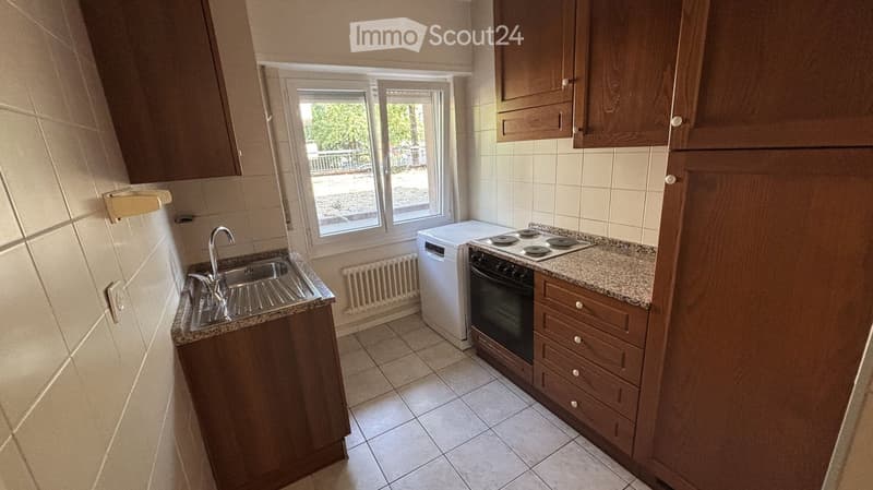 Compact kitchen with wooden cabinets, granite countertop, sink, oven, and dishwasher.