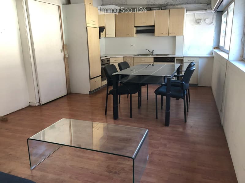 Open-plan living and dining area with wooden flooring, glass coffee table, dining table with chairs, kitchen area with cabinets, refrigerator, oven, sink, and dishwasher.