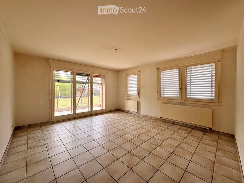 Empty room with tiled floor, large sliding glass doors, and radiators along the walls.