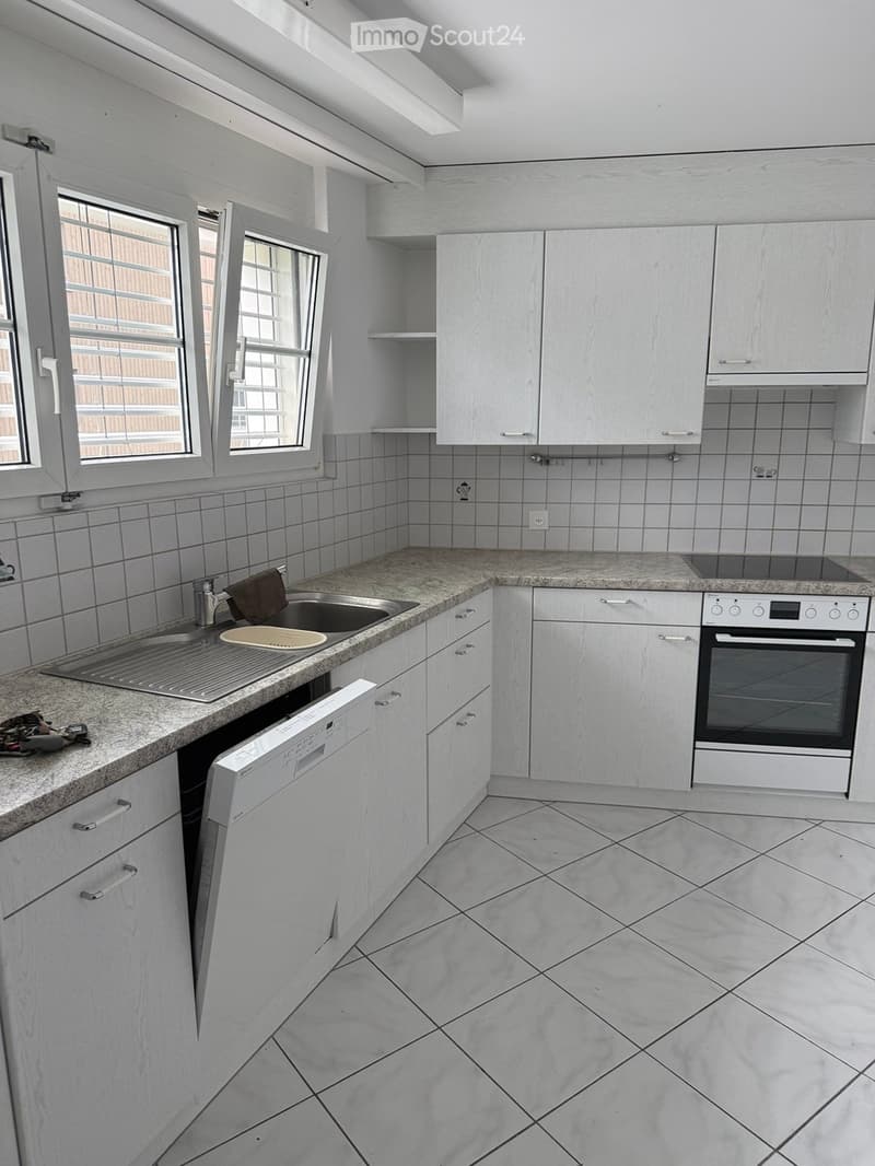 Modern kitchen with white cabinets, granite countertops, and tiled backsplash. Features a sink, dishwasher, and oven.