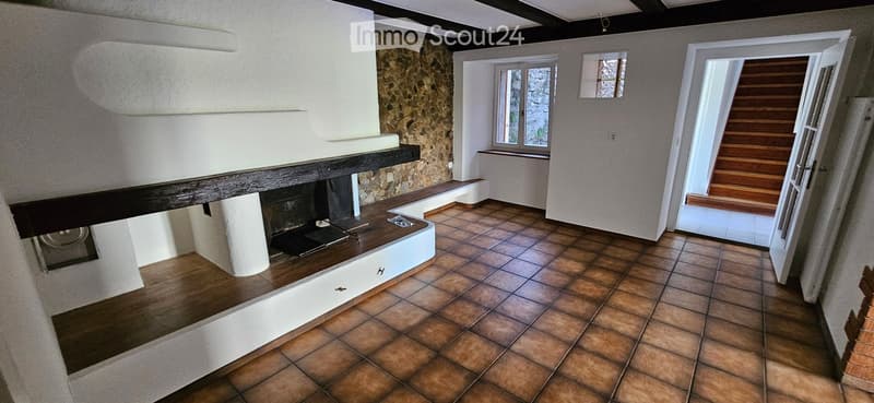 Empty room with tiled floor, fireplace, wooden bench, and open doorway leading to another space.