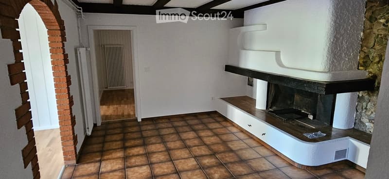 Hallway with a fireplace, tiled floor, white walls, and a wooden bench beside the fireplace.