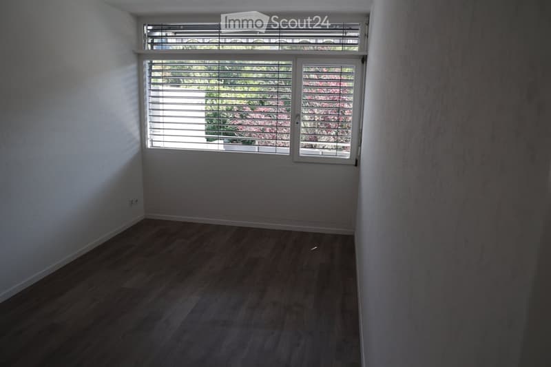 Empty room with wooden flooring, white walls, and large windows with blinds. No furniture or equipment present.