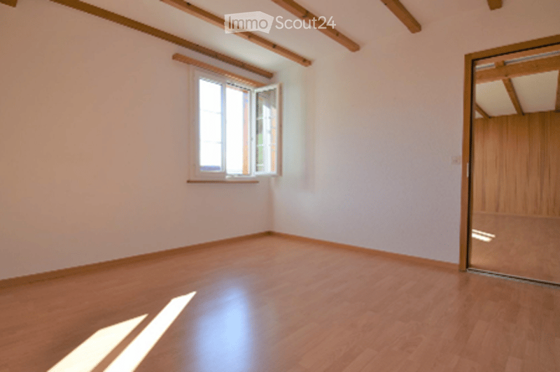 Empty room with wooden flooring, white walls, and a large window with blinds. No furniture or equipment present.