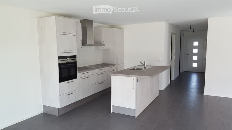 Modern kitchen with white cabinets, stainless steel appliances, island, and dark tiled floor.