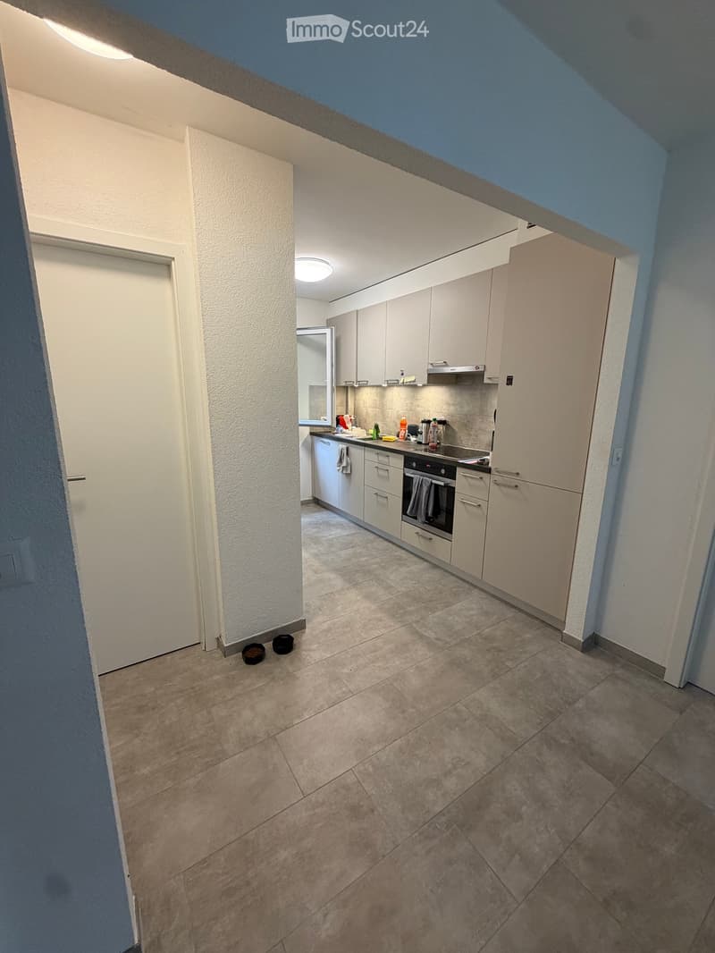 Modern kitchen with white cabinets, stainless steel appliances, and tiled flooring.