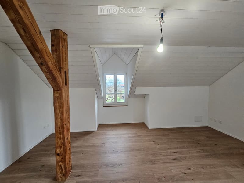 empty room, wooden floors, wooden support beams, slanted ceiling, small attic window