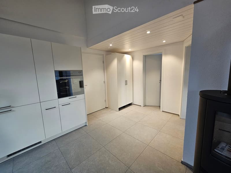 Empty kitchen with a modern design. White cabinets, tiled floor, and a fireplace.