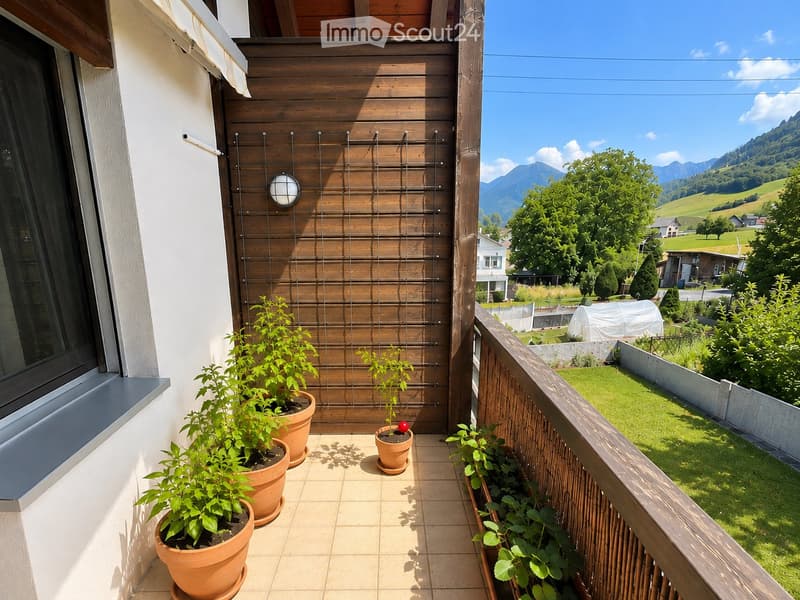 Balcony with wooden railing, potted plants, and scenic mountain view.