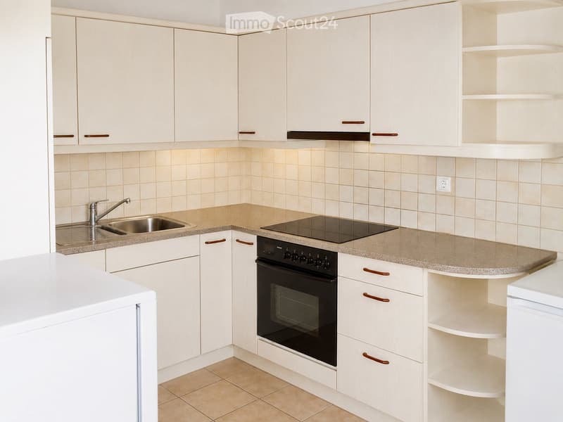 Modern kitchen with white cabinets, beige tiled walls, granite countertops, and stainless steel sink and faucet.