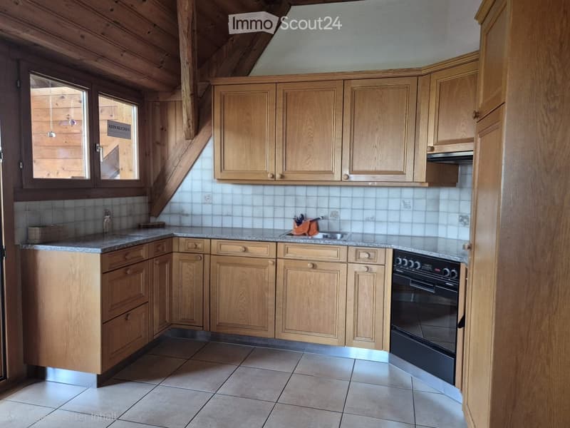 Bright kitchen with wooden cabinets, granite countertop, and built-in oven. Features a window with a view of the outside and tiled walls.