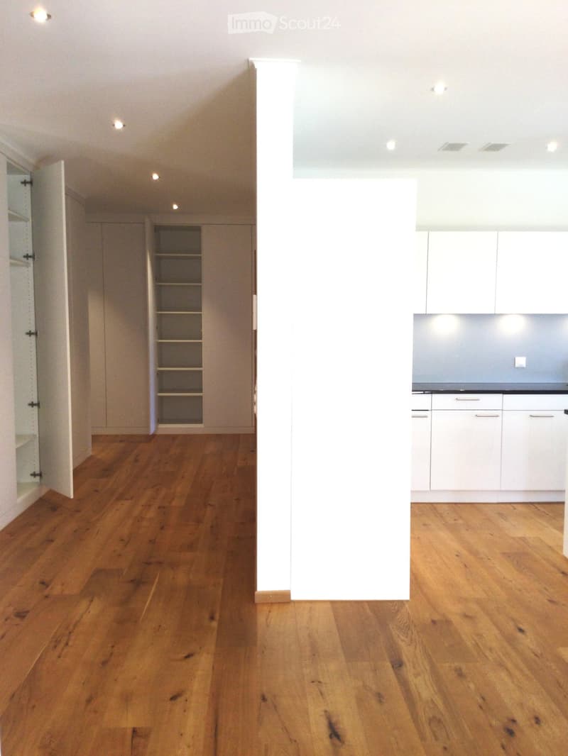 Empty room with wooden flooring, white walls, and built-in cabinets. No furniture or appliances present.