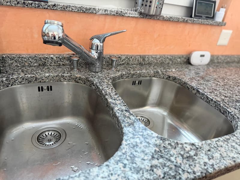 Stainless steel double sink with modern faucet on granite countertop.