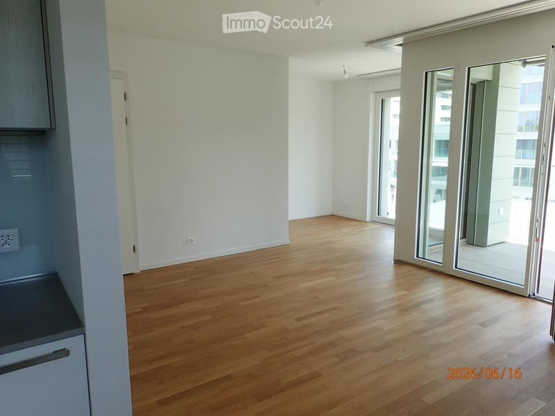 Empty room with wooden flooring, white walls, and large sliding glass doors leading to a balcony.