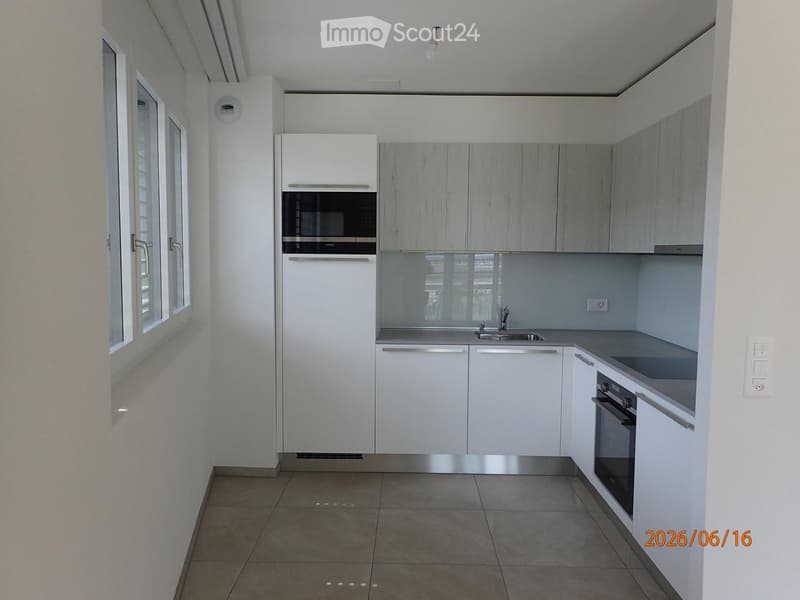 Modern kitchen with white cabinets, stainless steel appliances, and a light grey countertop.