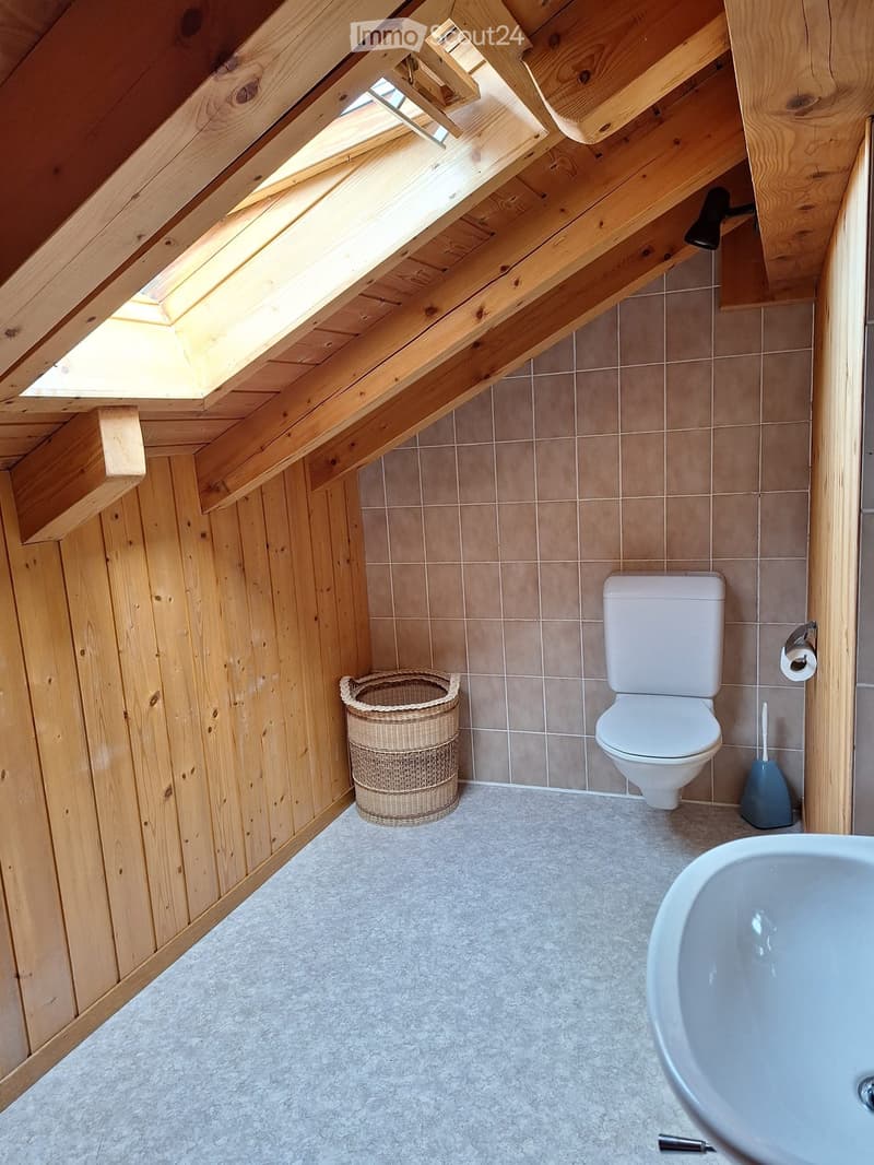 Bathroom with wooden walls, tiled floor, toilet, bathtub, wicker basket, and toilet brush visible.