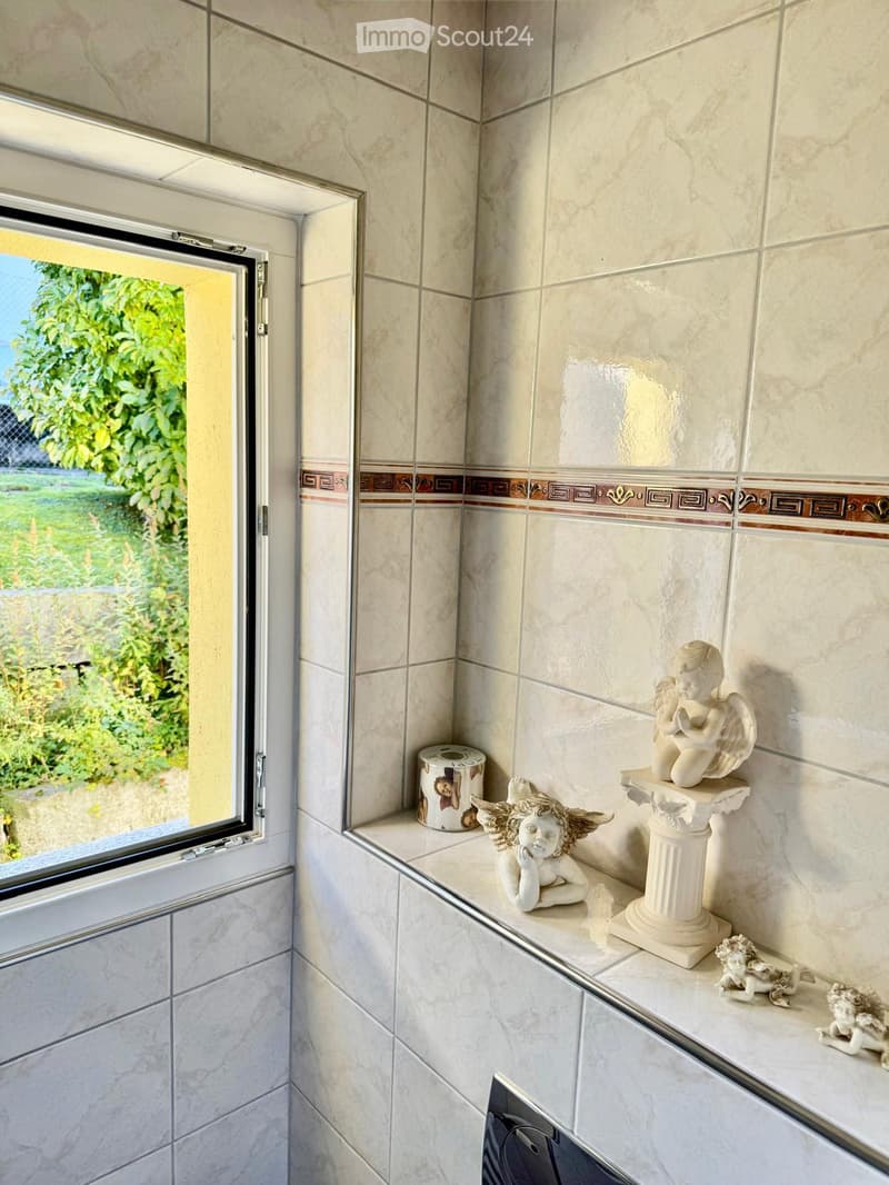 white tiled walls, small window, decorative angel statues on a shelf
