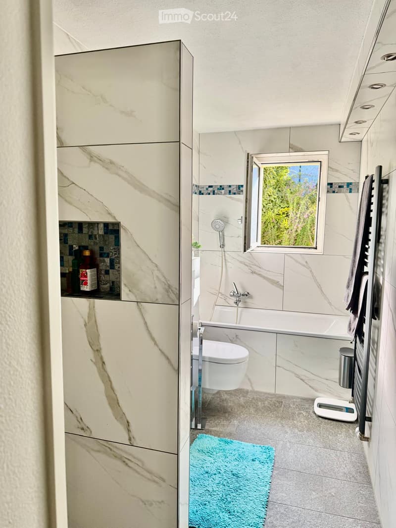 modern bathroom with marble tiles, bathtub, toilet, shower, towel rack, open window