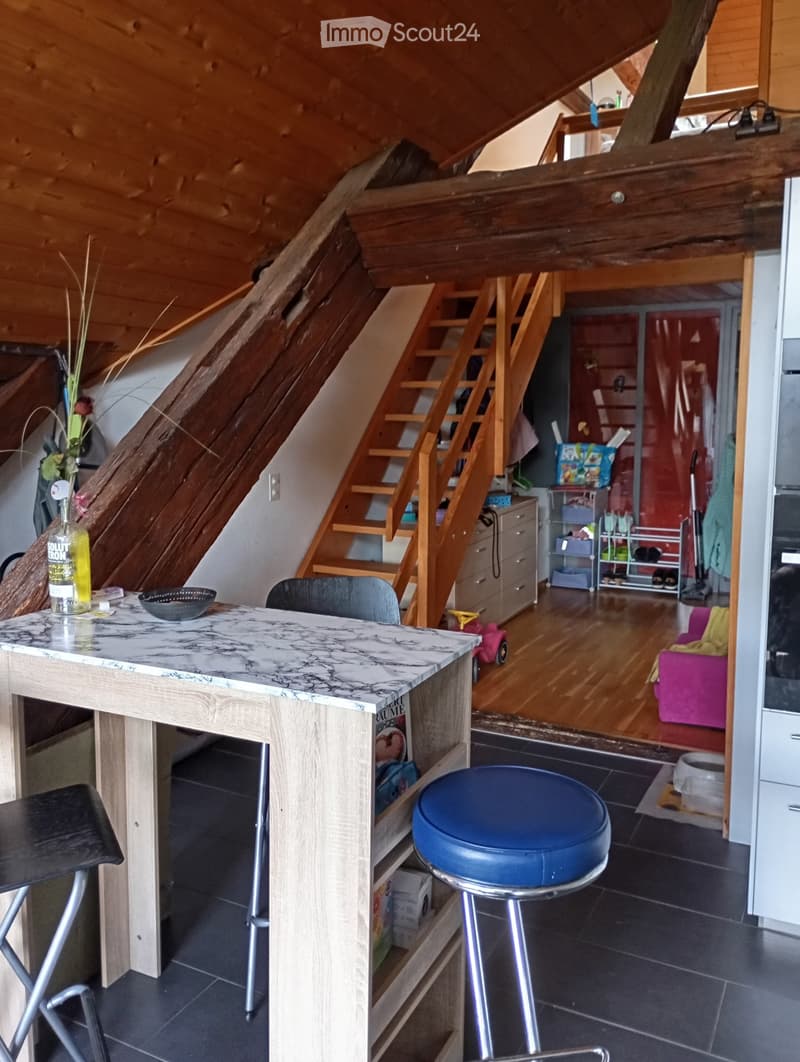 kitchen with dining area, wooden beams, wooden stairs, wooden floor, table, chairs, shelves, cabinet, drawers, flower vase, bottle, bowl, toy car, rug, couch, bowl, storage box, shoe rack, power outlet, power strip