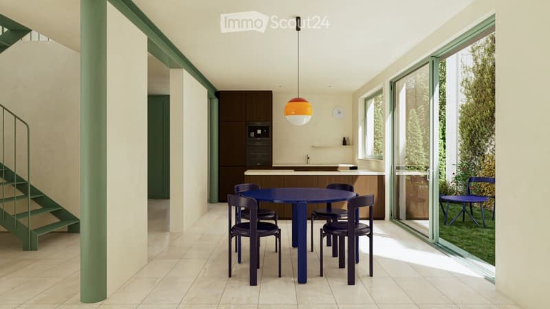 Modern kitchen and dining area with a blue dining table, chairs, and a pendant light. The kitchen features dark cabinets and a white countertop.