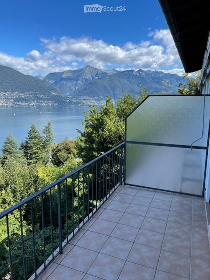 Balcony with tiled floor, metal railing, and scenic mountain and lake view.