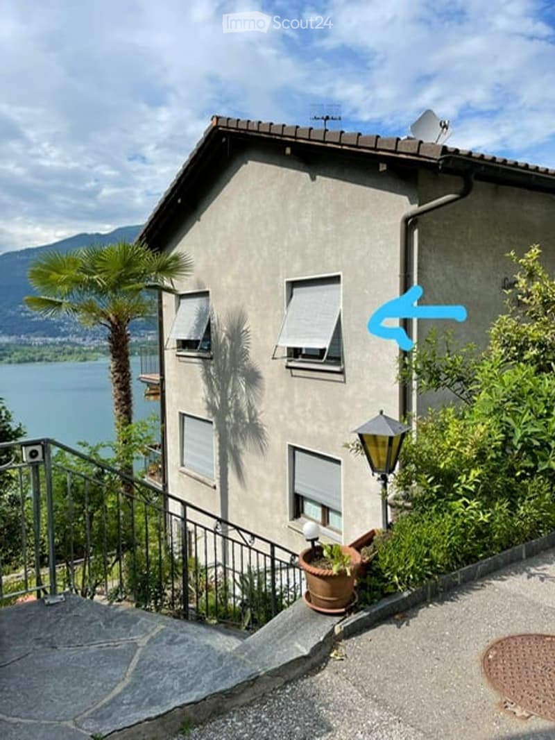 Two-story house with a view of a lake and mountains, featuring a staircase leading up to the entrance.