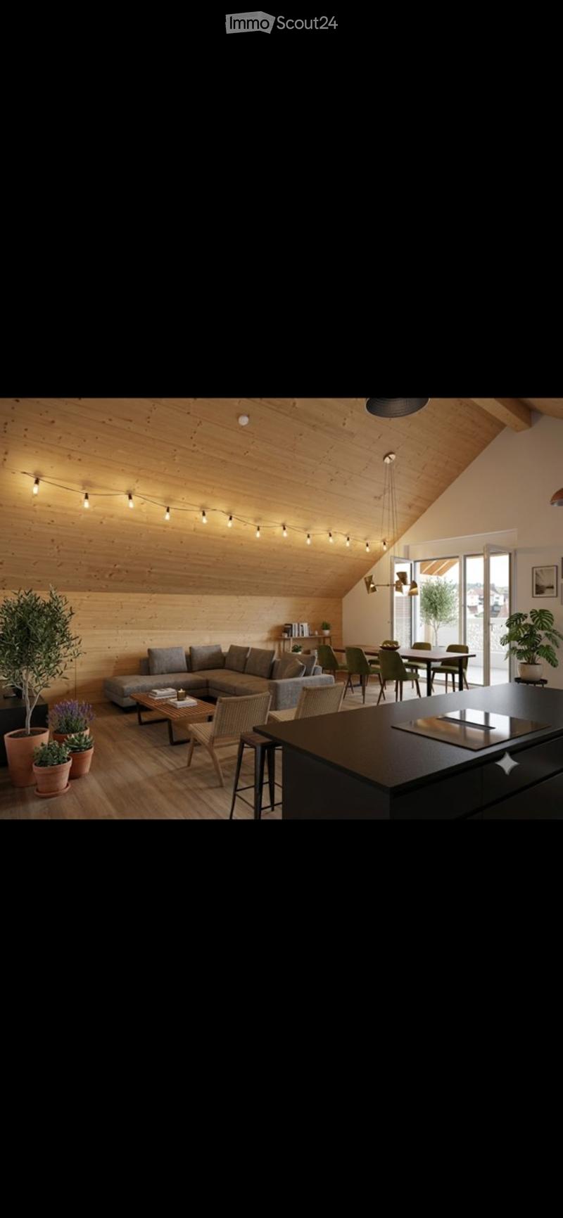 Open-concept living and dining area with a modern aesthetic. Features a grey sectional sofa, coffee table, dining table with chairs, kitchen island, and several potted plants. The space has wooden walls and ceiling with string lights.
