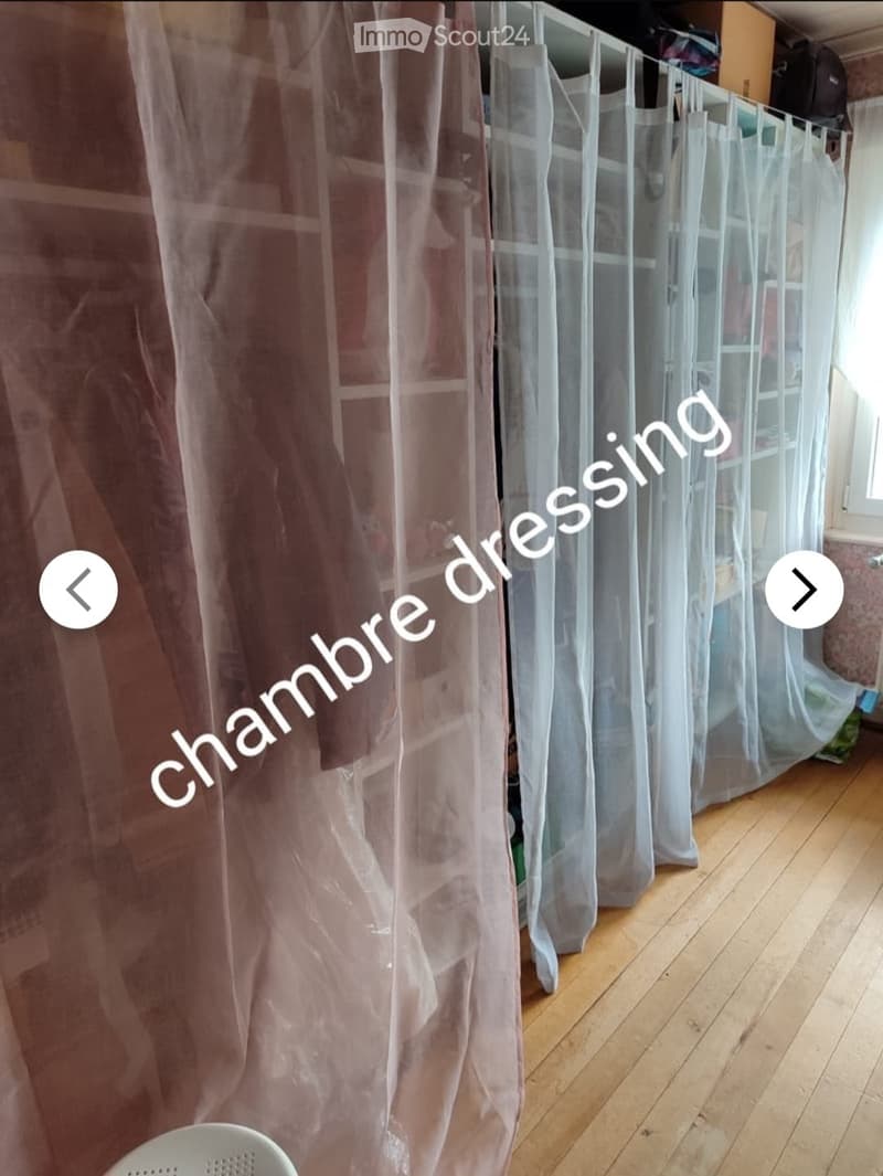 Empty room with wooden flooring and sheer curtains partially drawn, no furniture or equipment visible.