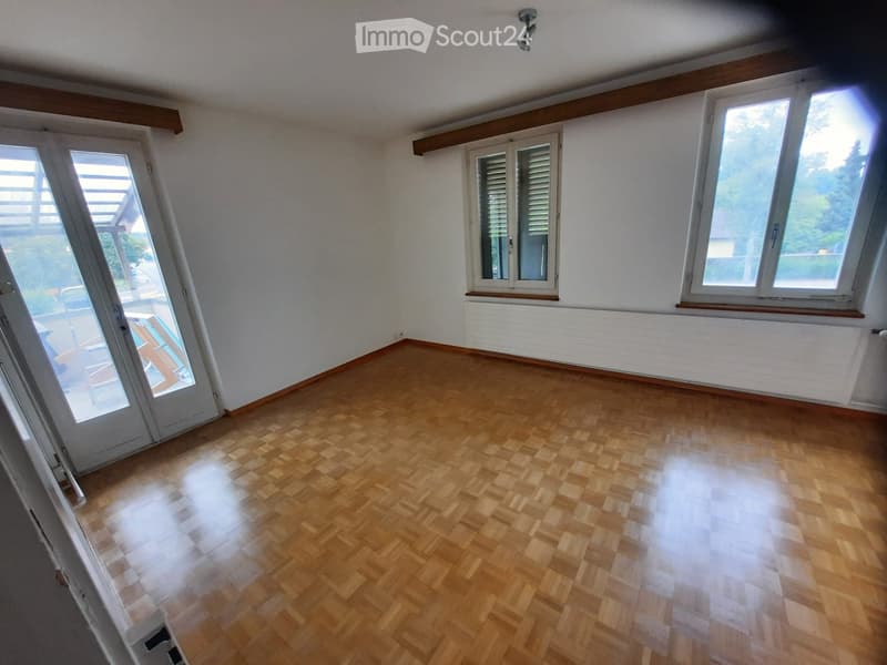 Empty room with wooden flooring, white walls, large windows, and a door leading to a balcony area.
