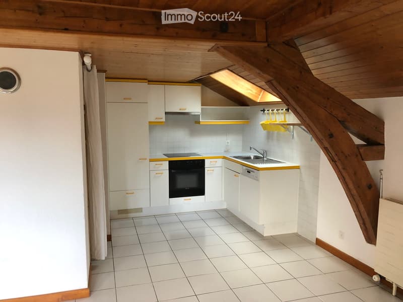 Compact kitchen with white cabinets, stainless steel appliances, and a wooden staircase leading to an attic space.