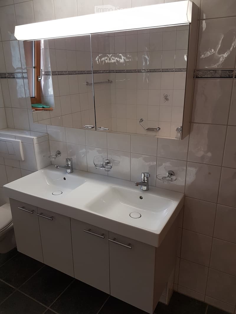 Bathroom with white vanity sink, mirror cabinet, and tiled walls