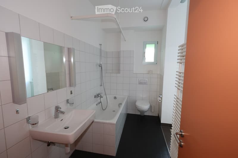 Bathroom with bathtub, toilet, mirror, sink, radiator, and window