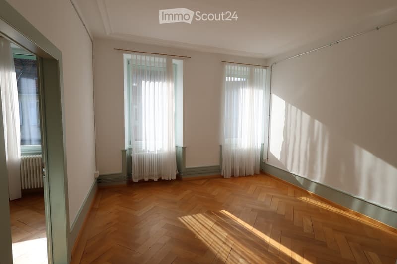 Parquet flooring, white walls, windows with white curtains, radiators