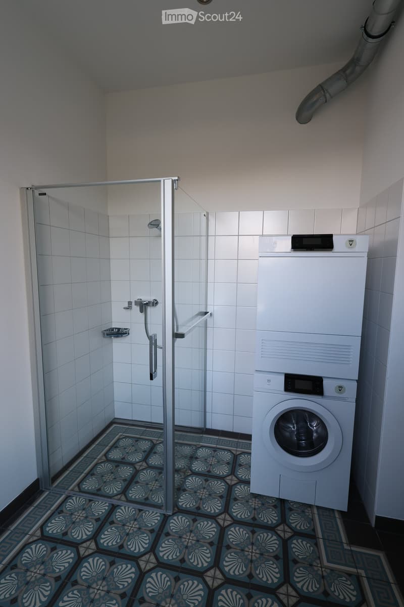 Bathroom with shower, white tiled floor, private washing machine, and dishwasher.
