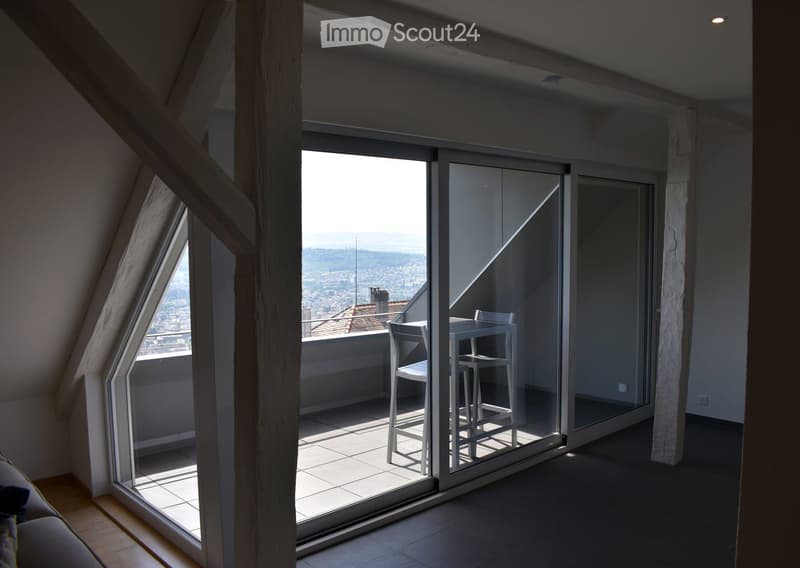 Modern balcony with large glass sliding doors, offering a scenic view, equipped with a small table and chairs.