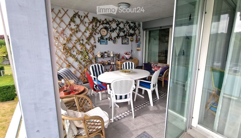 Balcony with table and chairs, decorative plants, glass doors, tiled floor