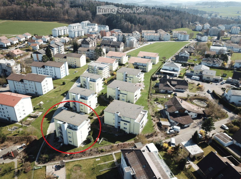 Aerial view of a residential area with multiple apartment buildings, houses, and green spaces.