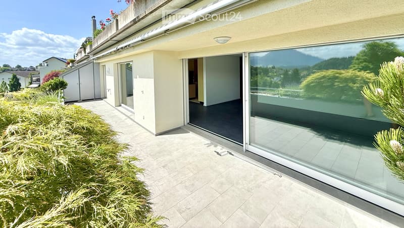 Modern balcony with large glass sliding doors, tiled floor, and scenic mountain view.