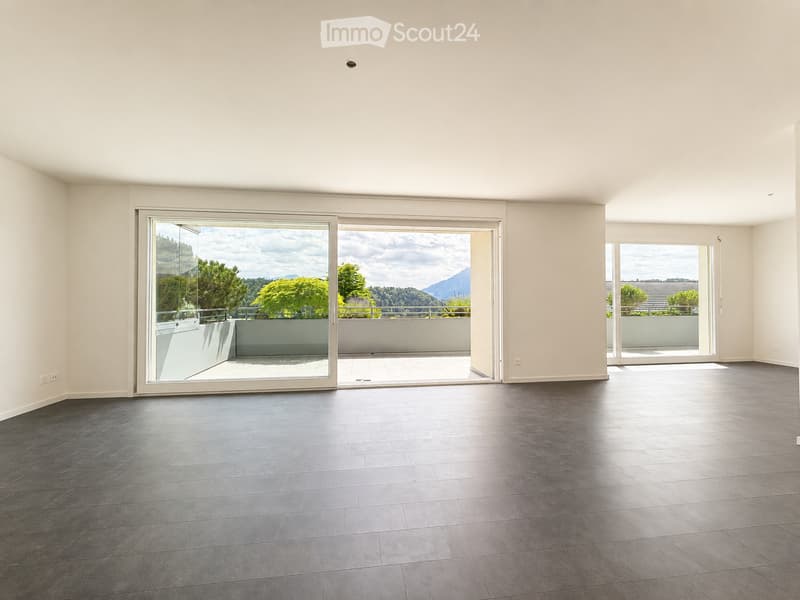 Empty room with dark tiled floor, large sliding glass doors leading to a balcony with scenic mountain view.