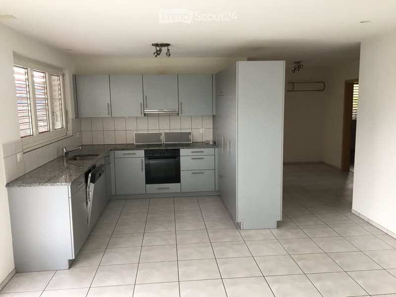 Modern kitchen with grey cabinets, granite countertop, stainless steel appliances, and tiled flooring.