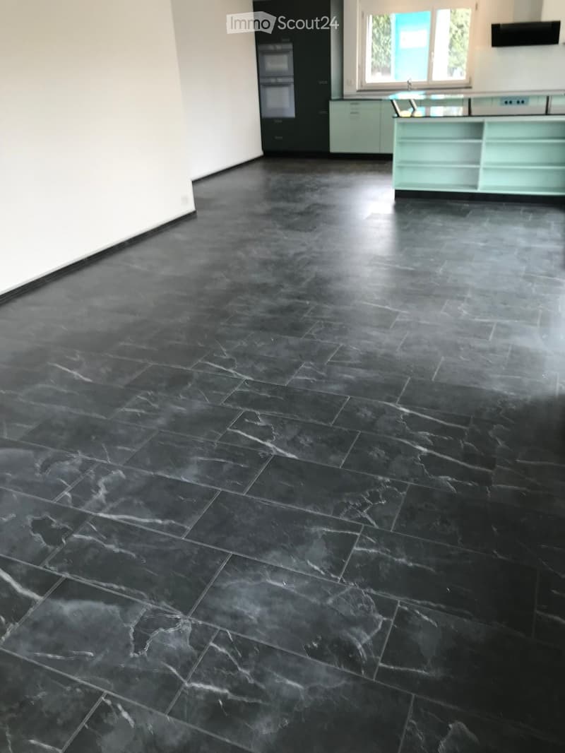 Empty room with dark, polished marble tiles on the floor and light-colored walls. No furniture or equipment is present.